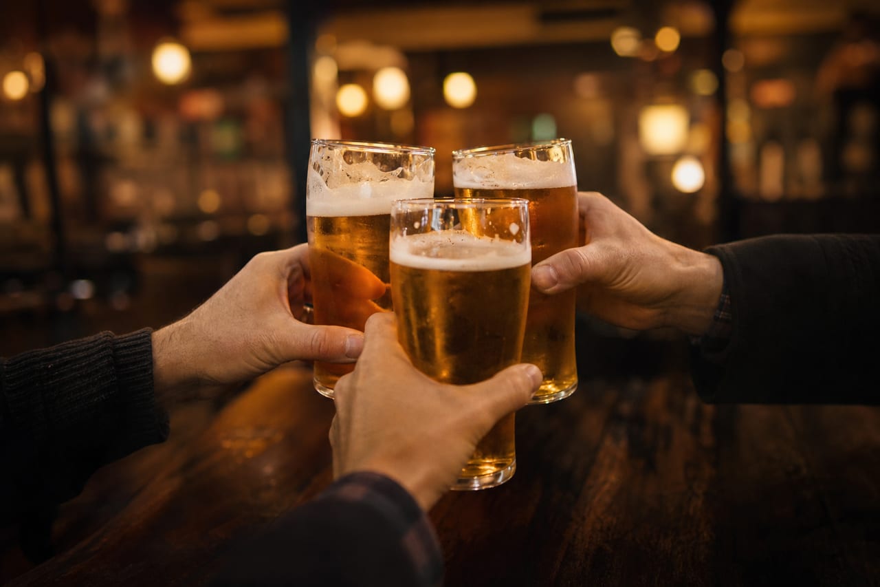 Friends clinking pints at the bar