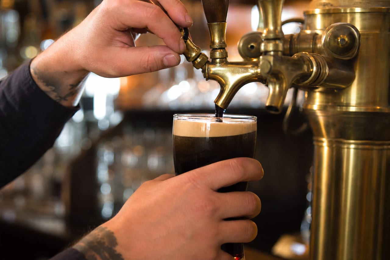 A pint of stout being poured from a tap